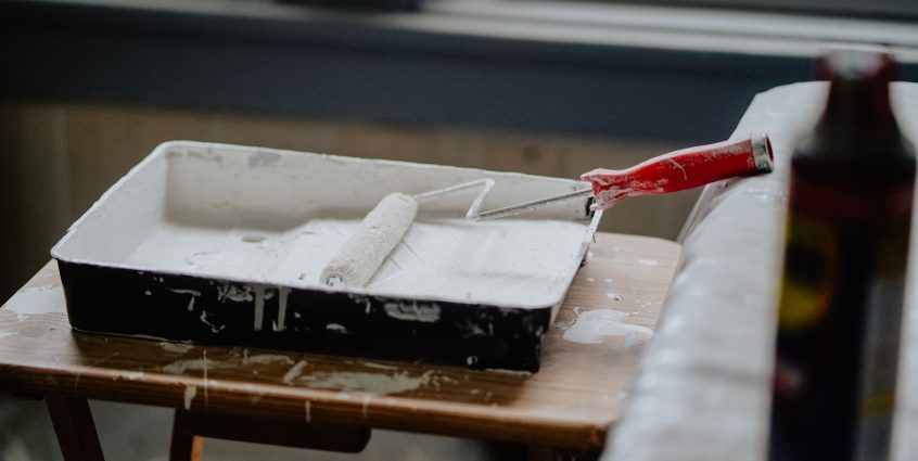 A paint roller and tray with white paint on a wooden table, indicating a renovation work. — Antivirus For Google android - Wo