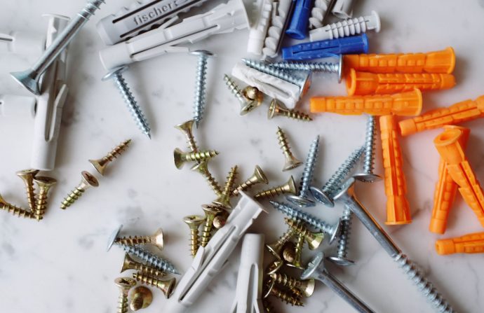 Set of various multicolored plastic dowels with metal screws of different sizes placed on white marble table in modern worksh