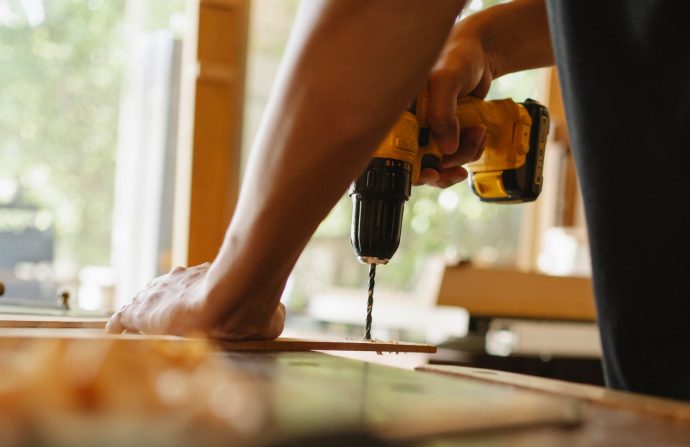 Crop anonymous male drilling timber plank with professional screwdriver on table in workshop — Avira Review