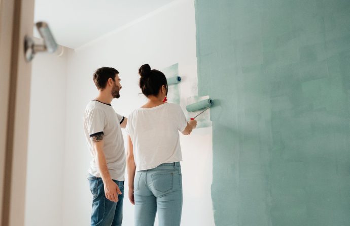 A couple collaborates to paint a wall with a roller indoors, showcasing teamwork. — Business Consulting as well as the SLA