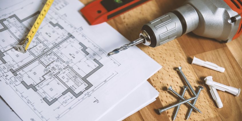 Close-up of construction blueprint with tools like drill and screws on a wooden table. — Business Process Motorisation Softwa