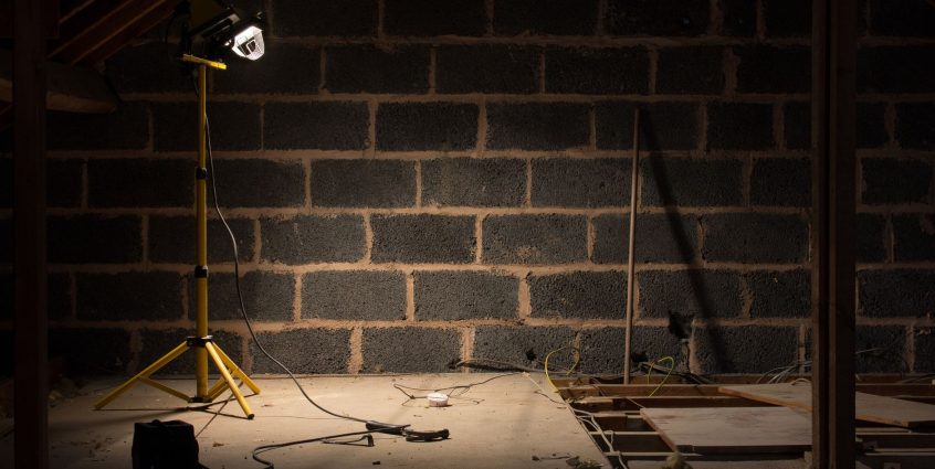 A dimly lit attic space under renovation with a construction lamp illuminating the scene. — Casinochan Quebec