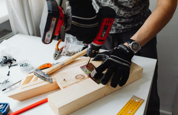 A craftsman uses a power drill on wood, showcasing carpentry tools and skills. — Cheekylovers Bewertung