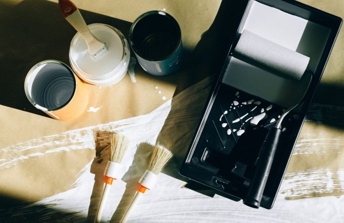 Top view of painting tools including brushes, rollers, and paint cans on paper. — Custom Essays and Writing Services