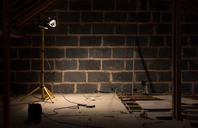 A dimly lit attic space under renovation with a construction lamp illuminating the scene. — Dentistas En Madrid