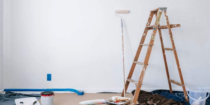 A room prepared for renovation with a ladder, paint supplies, and drop cloth. — Edarling Review  2021