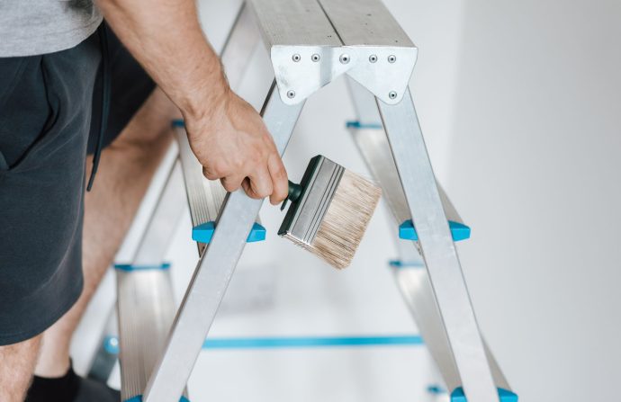 Side view of crop anonymous male master standing on ladder with tool while painting walls in flat — Features of Data Computer