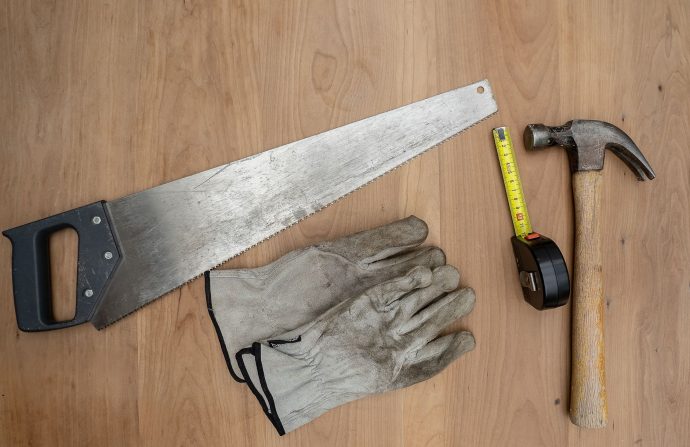 Flat lay of essential carpentry tools including a saw, hammer, and tape measure on wooden surface. — Food Processing Equipmen