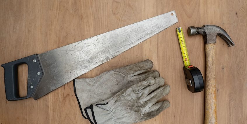 Flat lay of essential carpentry tools including a saw, hammer, and tape measure on wooden surface. — Food Processing Equipmen