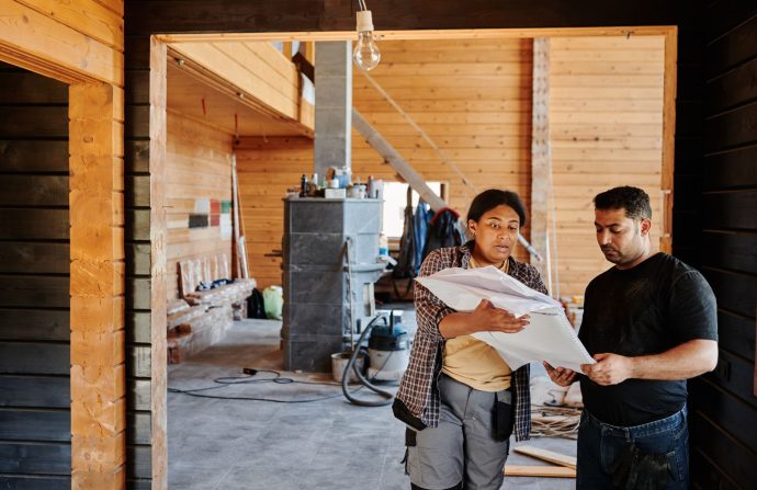 Construction workers reviewing blueprints indoors at a renovation site with wooden walls. — G Data Antivirus security softwar
