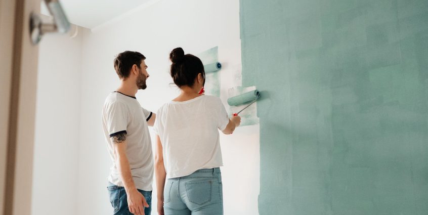 A couple collaborates to paint a wall with a roller indoors, showcasing teamwork. — How to Choose a Electronic Data Room Revi