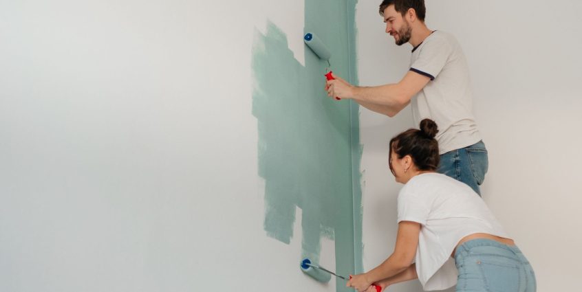 A young couple collaborates on painting a wall with rollers, highlighting teamwork and home improvement. — How To Prepare Hom