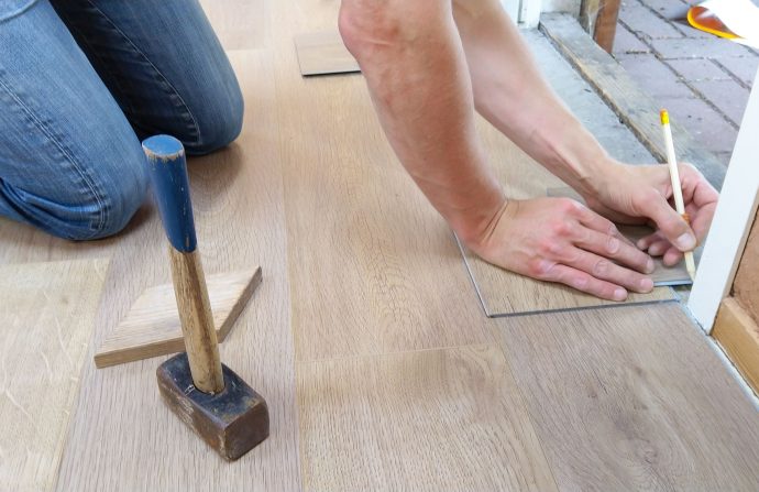 A craftsman carefully measures and marks wooden floor panels for precise installation. — How you can Qualify For a Competitiv