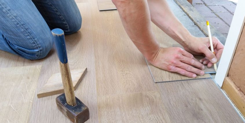 A craftsman carefully measures and marks wooden floor panels for precise installation. — How you can Qualify For a Competitiv