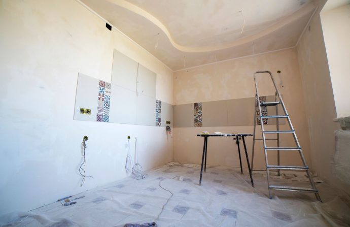 Interior view of a room under renovation with paint, tiles, and tools. —