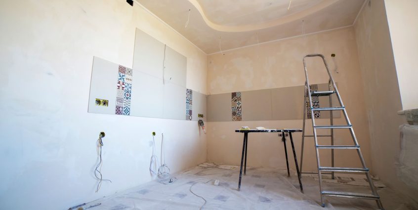 Interior view of a room under renovation with paint, tiles, and tools. —