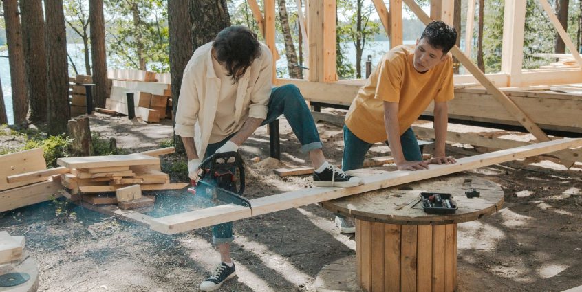 Two adult men working on wood construction project outdoors, using a chainsaw. — Ladies Show The Things They Enjoy & Hate Abo