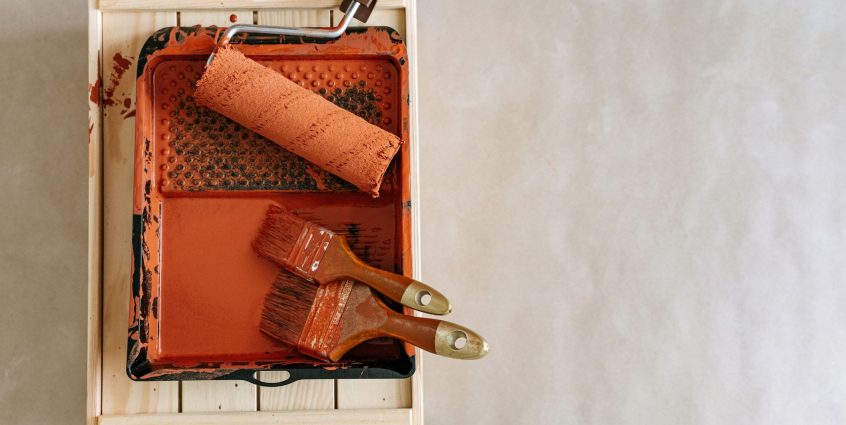 An overhead shot of paintbrushes and a roller in a tray, perfect for home renovation projects. — Online Board Gatherings Guid