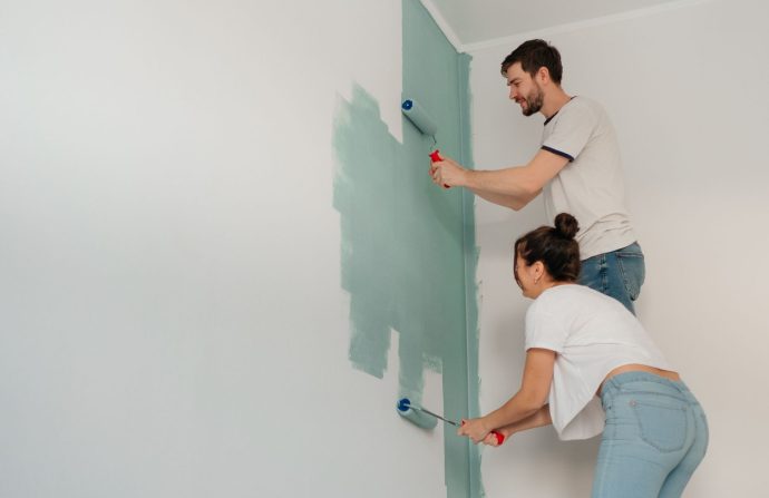 A young couple collaborates on painting a wall with rollers, highlighting teamwork and home improvement. — Research Paper Ass