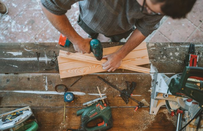 Craftsman busy drilling wooden planks in a carpentry workshop with various tools around. — So what can Ladies Learn About men