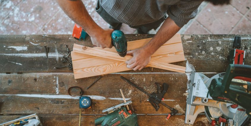 Craftsman busy drilling wooden planks in a carpentry workshop with various tools around. — So what can Ladies Learn About men