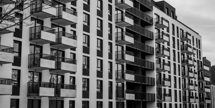 Black and white photo of a contemporary apartment building with multiple balconies. — Tenant Screening Credit Check Identifie