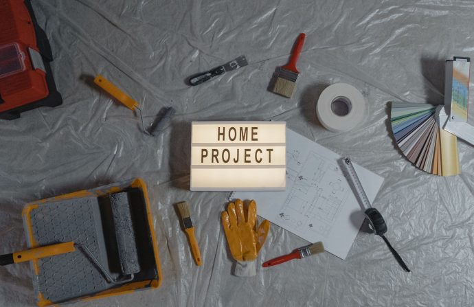Flat lay of home improvement tools, paint samples, and blueprints for a DIY project. — The Benefits and Risks of Overseas Dir