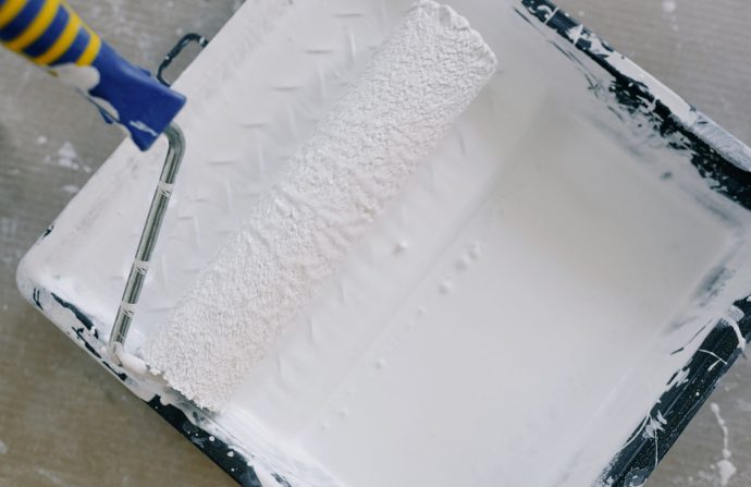 Top view paint roller placed in black tray filled with white pigment and placed on floor in renovating apartment — The Best D