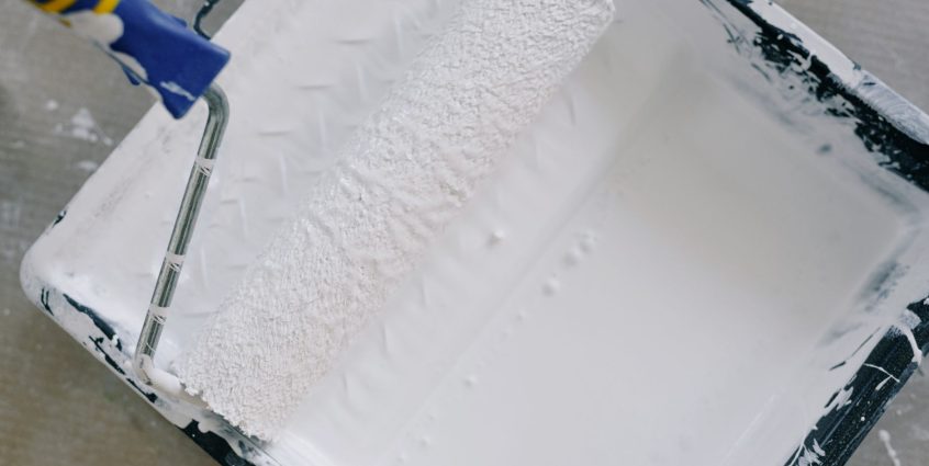 Top view paint roller placed in black tray filled with white pigment and placed on floor in renovating apartment — The Best D