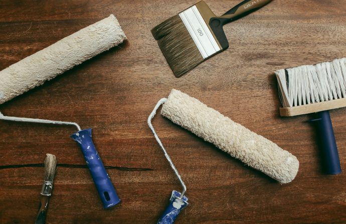 Top view of various painting tools including rollers and brushes laid out on a wooden surface. — The Importance of Data Super