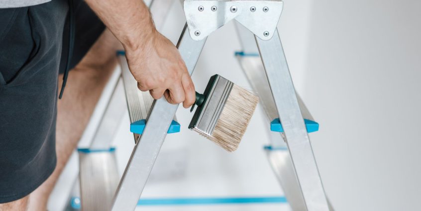 Side view of crop anonymous male master standing on ladder with tool while painting walls in flat — Tips on how to Fix a Stea