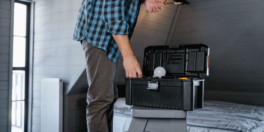 Person in plaid shirt fixing a light bulb using a toolbox in a rustic attic interior. — Vegan Romance: Veggie Singles Get 73%