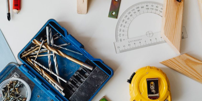 A selection of carpentry tools including drill bits, measuring tape, and protractor in an overhead shot. — What Is an Researc